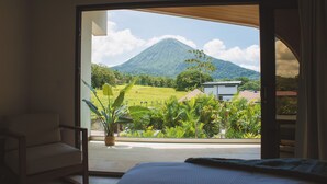 A bedroom with a large window offering a view of a mountain and lush greenery. - Fortuna Retreat (La Fortuna)