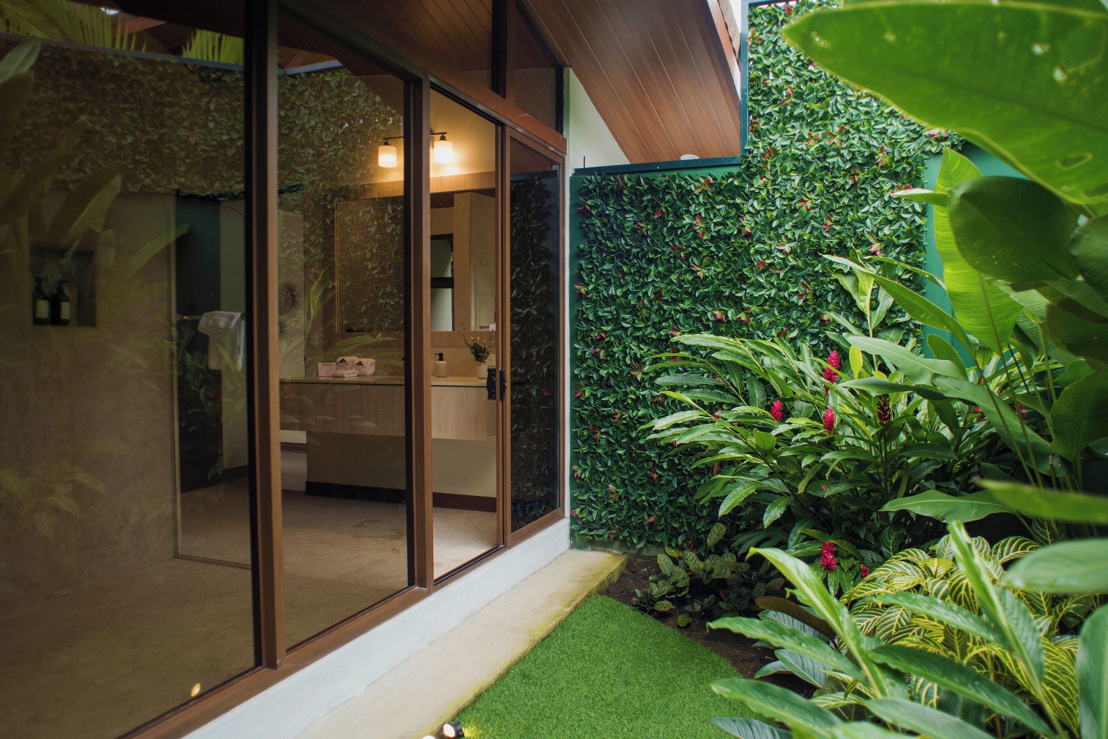 Une salle de bain moderne dotée d’une porte en verre, d’un espace douche et d’un mur végétal.