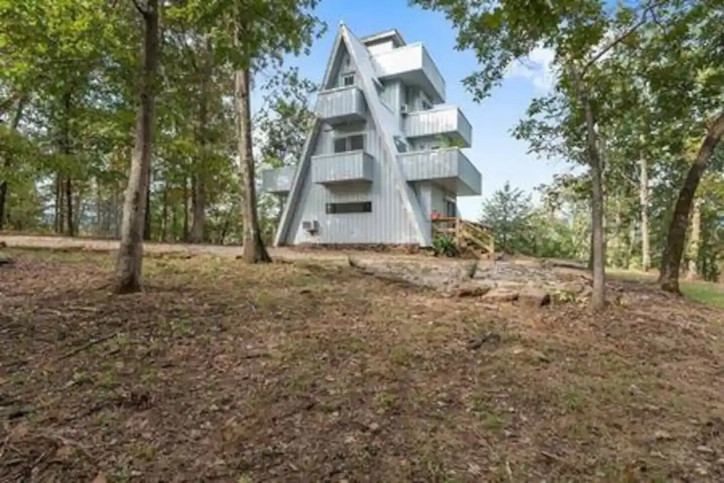 En modern, flervåningsbyggnad med balkonger, omgiven av träd i ett skogsområde.