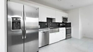 A modern kitchen with stainless steel appliances, white cabinetry, and a black countertop backsplash. - Modern A-FRAME cabin in the Ozark Mountains with amazing views! (West Fork)