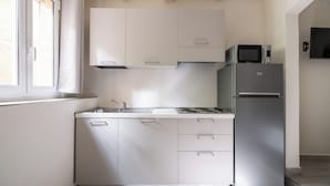 A modern kitchen with white cabinets, a stainless steel refrigerator, and a microwave. - Studio Fondazza 22 by Wonderful Italy (Bologna)