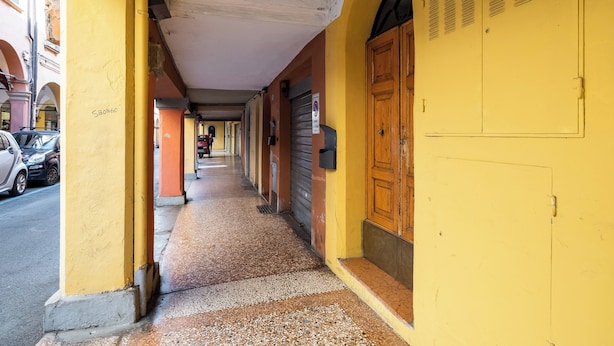 A narrow alleyway with yellow walls and a wooden door on the right. - Studio Fondazza 22 by Wonderful Italy (Bologna)