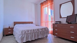 Un dormitorio con cama, cómoda, espejo y ventana con cortinas.