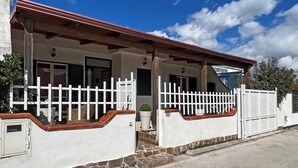 Una casa de dos pisos con fachada blanca, techo rojo y valla de piquete blanca.
