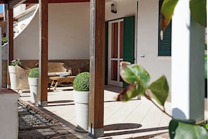 Un espacio de estar al aire libre con techo, muebles de mimbre y plantas en macetas.