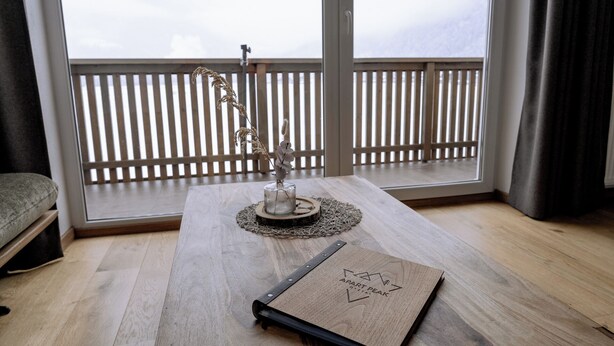 A room with a wooden table, a decorative vase, and a notebook. - Apart Peak Ötztal  (Laengenfeld)