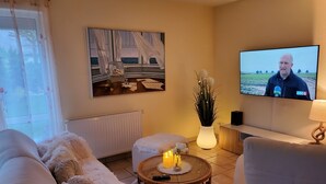Una sala de estar con un sofá, una mesita de centro con velas, un televisor y un cuadro en la pared.