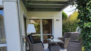Un patio exterior con mobiliario de mimbre, una mesa y una lámpara.