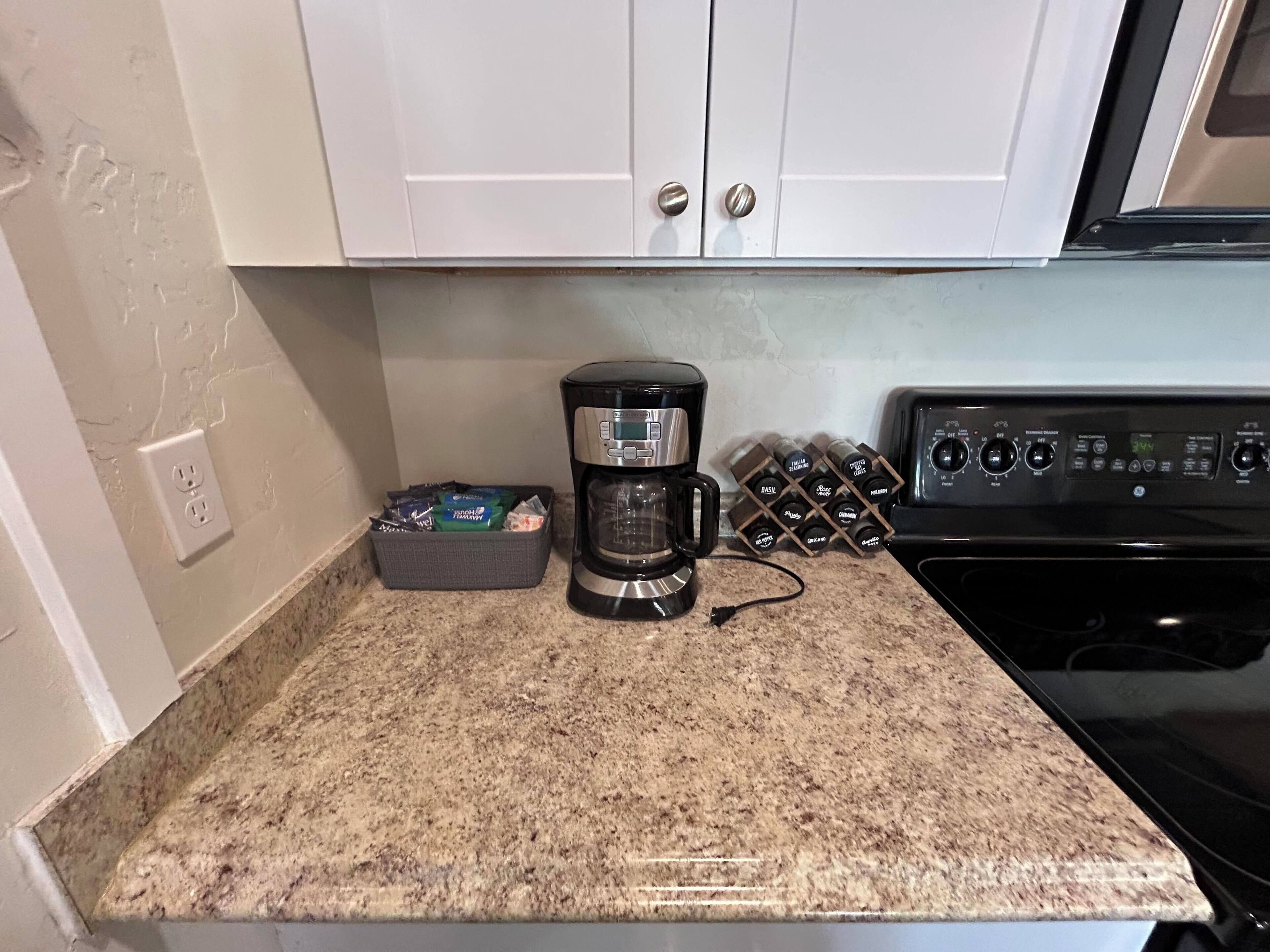 Una cocina con cafetera, una cesta de aperitivos y un enfriador de vino.