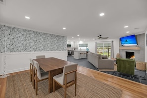 Una sala de estar moderna con comedor, cocina y chimenea.
