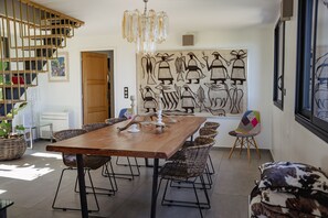 A dining area with a wooden table, wicker chairs, and a large wall mural.