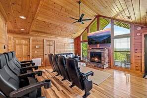 Interior acogedor de una cabaña con chimenea de piedra, paredes de madera y un ventanal grande con vistas a un paisaje pintoresco.