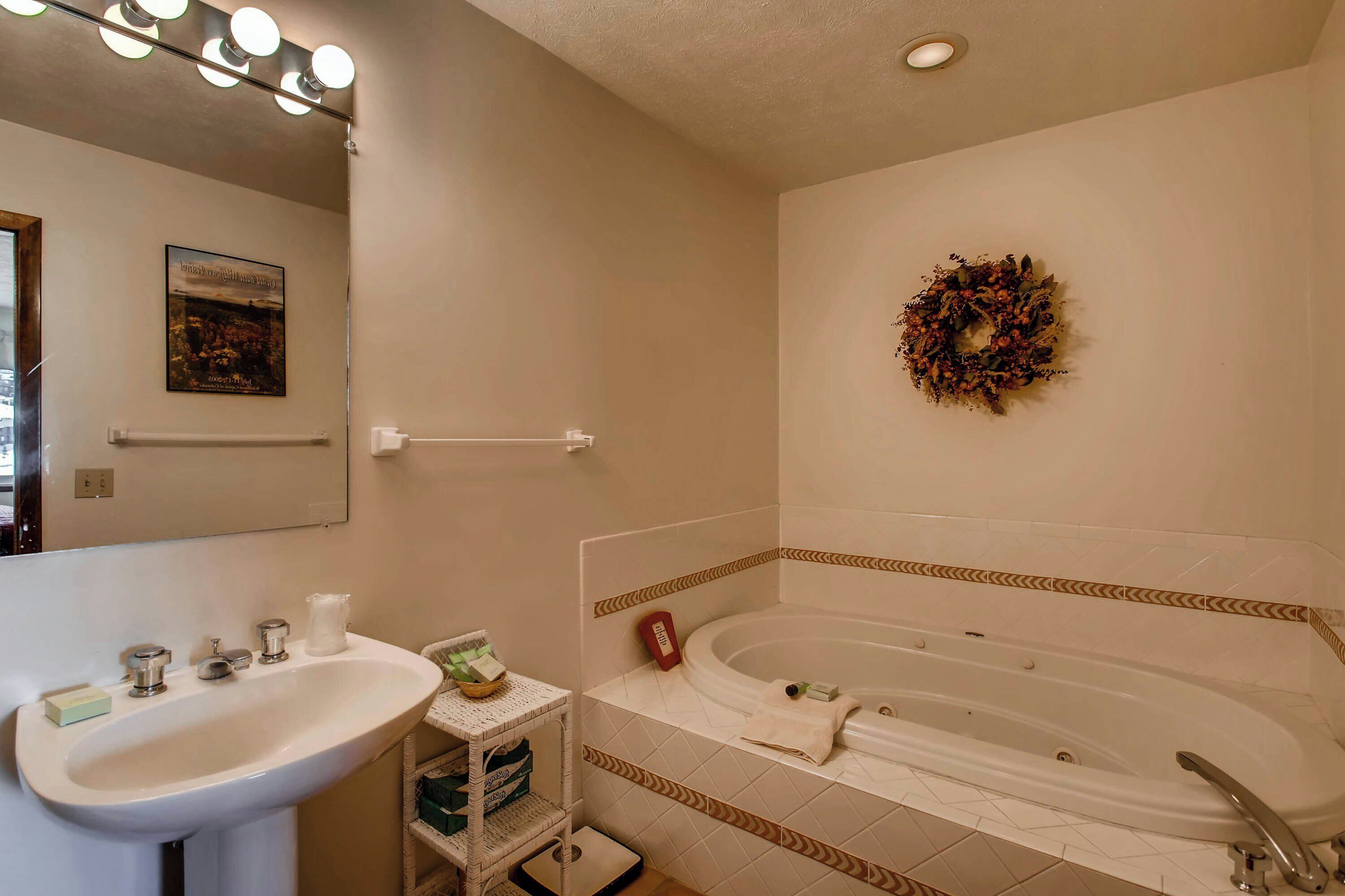 A bathroom with a sink, mirror, towel rack, and a bathtub.