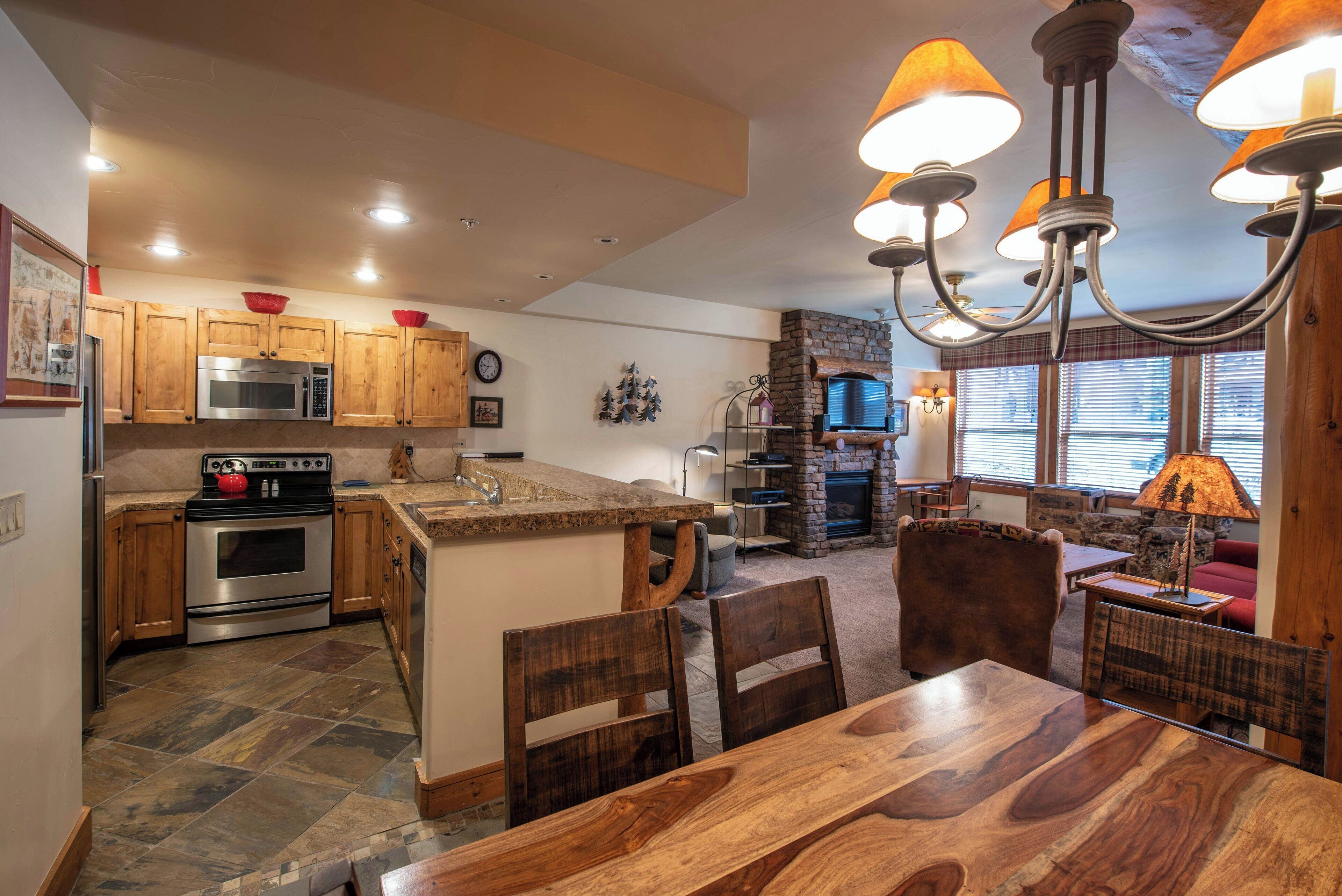 A kitchen with wooden cabinets, a built-in microwave, and a stone fireplace.