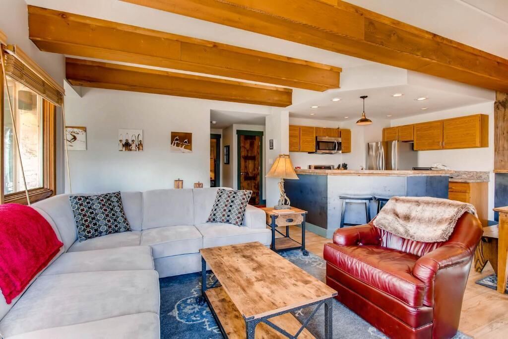 A modern living room with a sofa, a leather armchair, and a wooden coffee table.