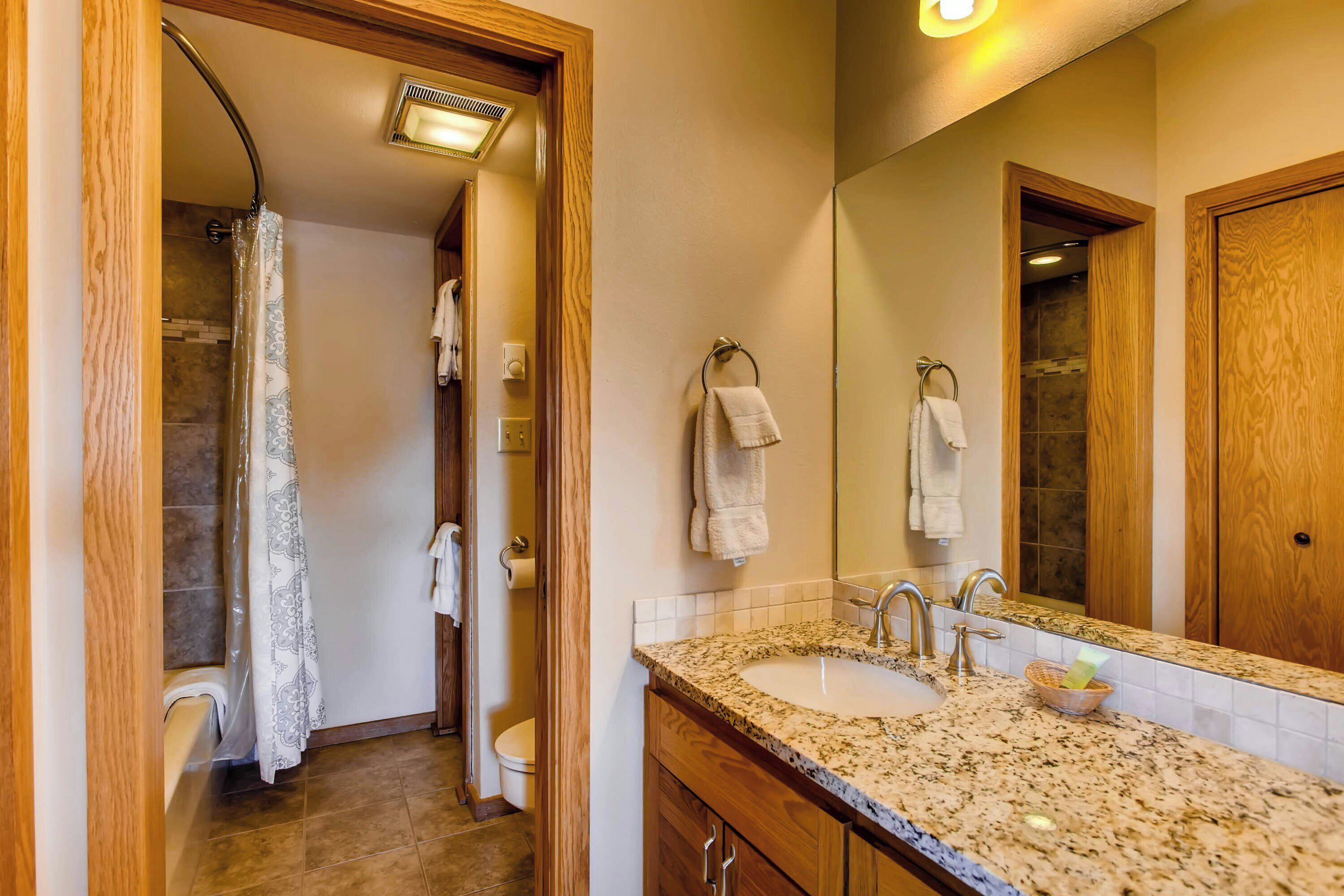 A bathroom with a sink, mirror, and shower.