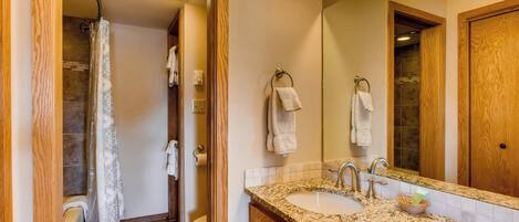 A bathroom with a sink, mirror, and shower.