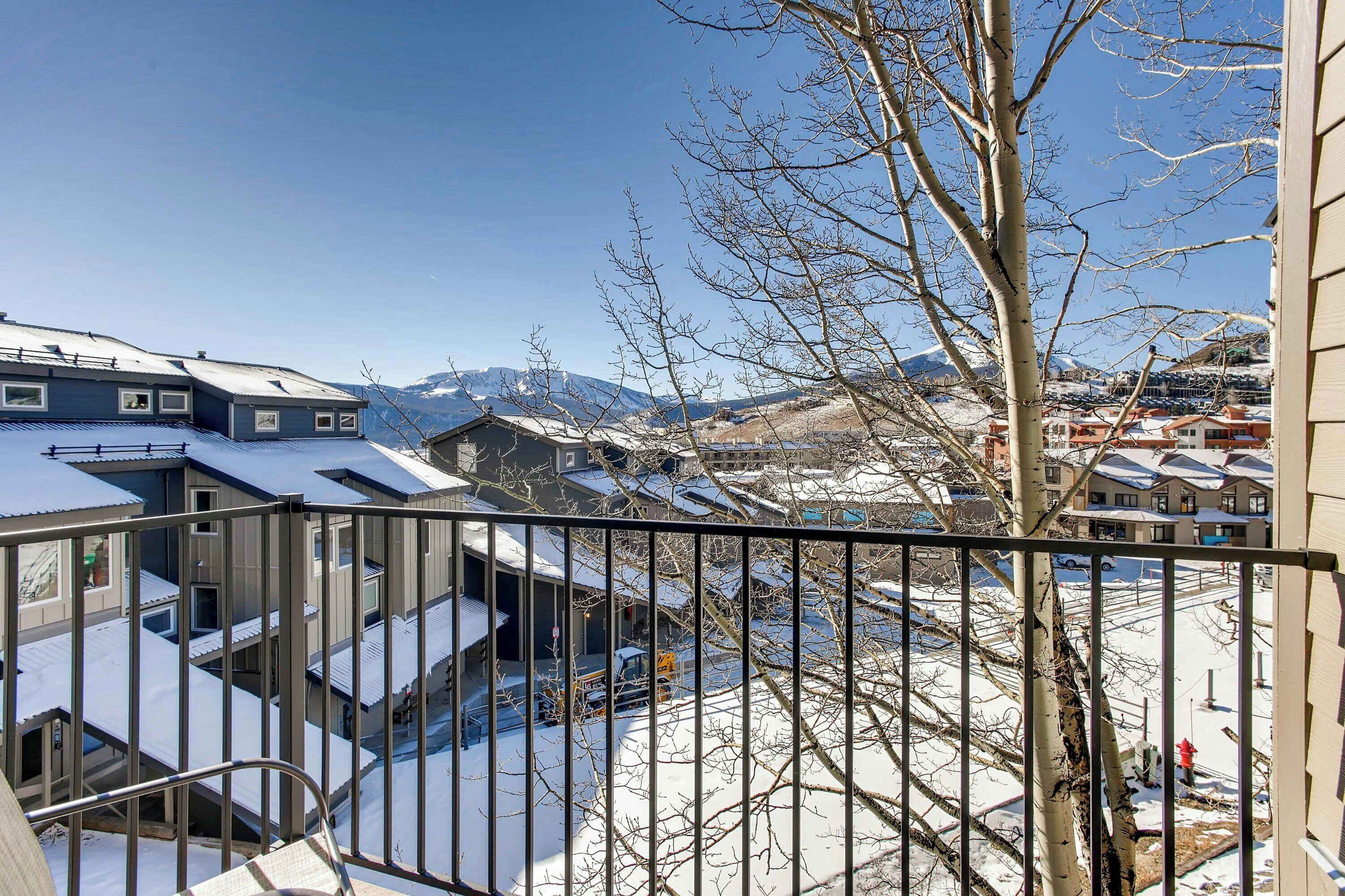 A residential area with snow-covered roofs and a clear view of mountains in the background.