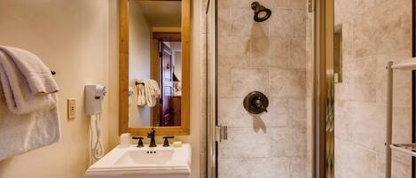 Une salle de bain équipée d’un lavabo, d’un miroir, d’un porte-serviettes et d’une douche à parois de verre.