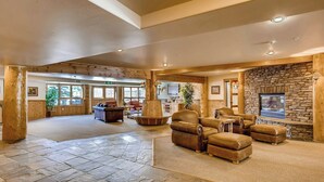A spacious lobby with stone flooring, leather furniture, a stone fireplace, and wooden beams. - Crested Butte Mountain Resort Properties by Vail Resorts (Crested Butte)
