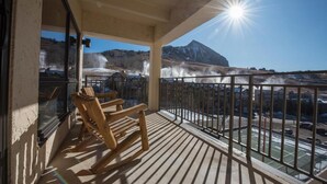 A balcony with wooden chairs, a railing, and a view of a mountainous landscape with a hot spring. - Crested Butte Mountain Resort Properties by Vail Resorts (Crested Butte)