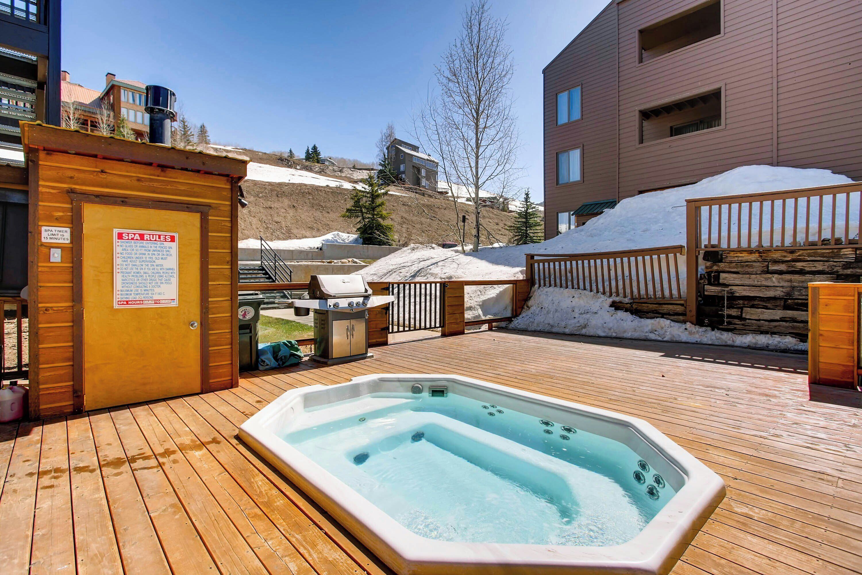 A wooden deck with a hot tub, a sauna, and a spa area with a sign indicating spa rules.