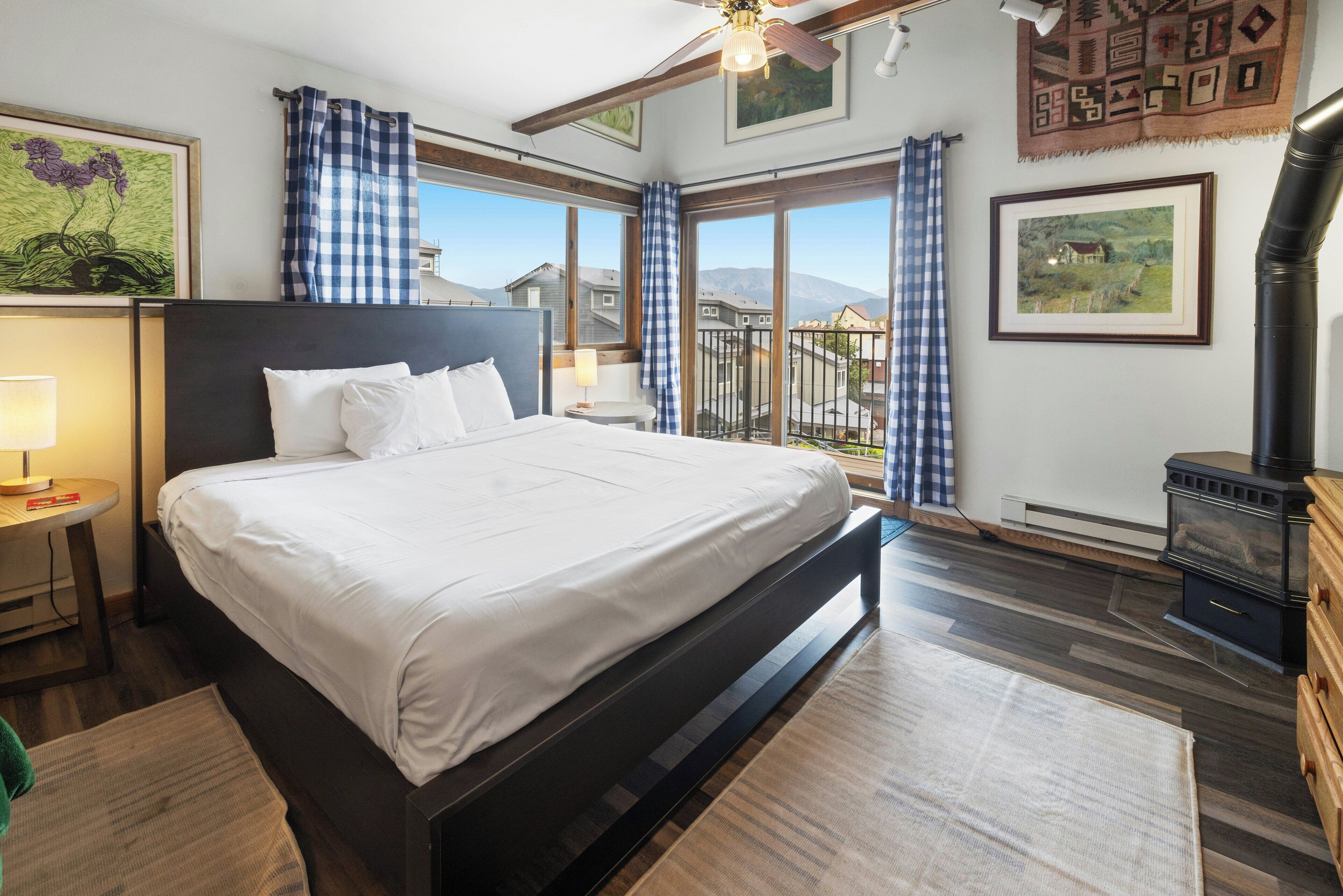 Quarto com uma cama grande, mesa de cabeceira, abajur, cômoda de madeira e lareira.
