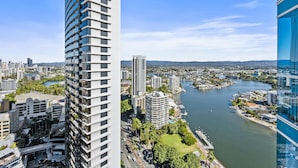 A high-rise building with a modern design, surrounded by other buildings and a river. - Two-Bedroom Apartment with Water View (SURFERS PARADISE)
