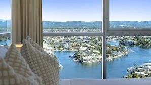 A room with a large window overlooking a marina and cityscape. - Two-Bedroom Apartment with Water View (SURFERS PARADISE)