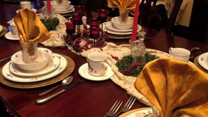 A formal dining table set with white plates, gold chargers, and clear glassware. - 1873 Victorian Rose B & B (Port Washington)
