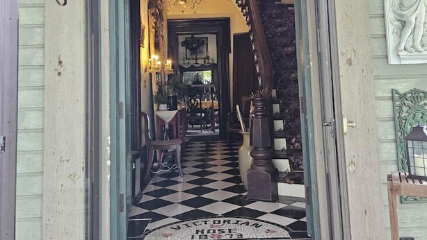 A grand entrance with a checkered floor, a staircase, and a chandelier. - 1873 Victorian Rose B & B (Port Washington)