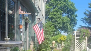 A garden with a fountain, a flag, and a wooden fence. - 1873 Victorian Rose B & B (Port Washington)
