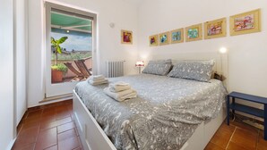 Un dormitorio con cama, ventana, radiador y una obra de arte en la pared.