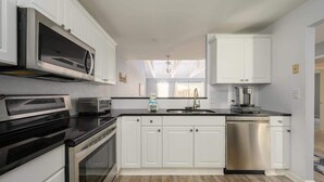 A modern kitchen with white cabinets, stainless steel appliances, and a black countertop.