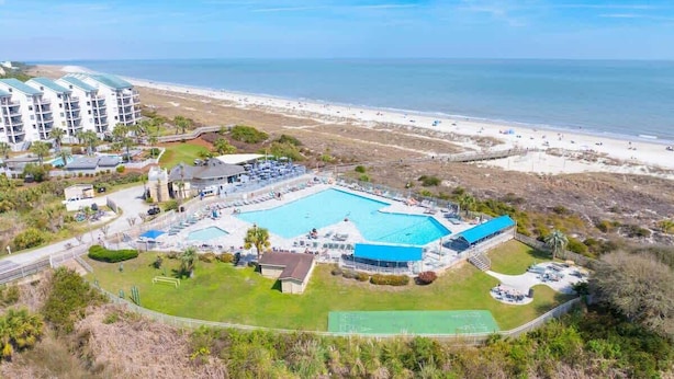 Um resort com uma grande piscina, acesso à praia e vários edifícios.