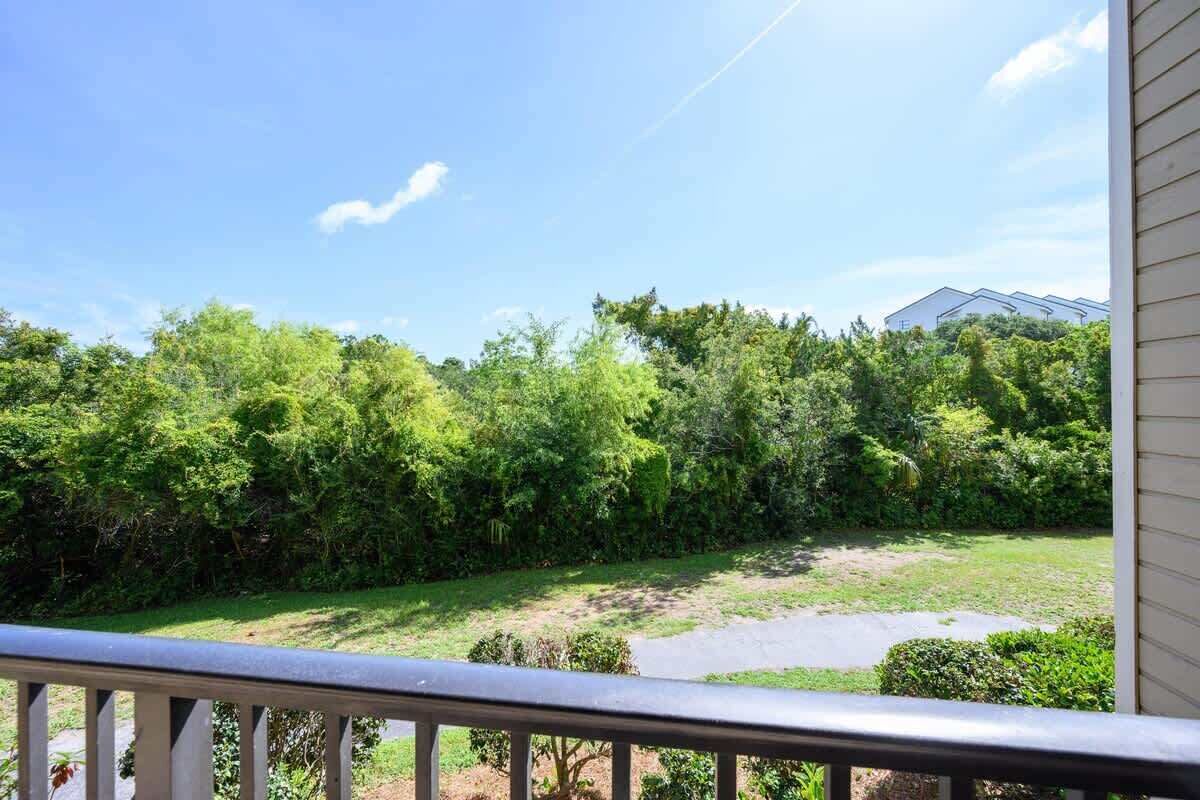 Une vue depuis un balcon donnant sur un jardin luxuriant, avec un feuillage dense et un ciel dégagé.