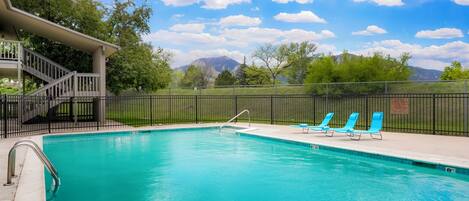 A swimming pool with a covered deck, a staircase, and lounge chairs.
