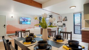 A modern dining area with a table set for four, a vase with white flowers, and a kitchen in the background. - Boulder Retreat w/ Pool & Mountain Views (Boulder)