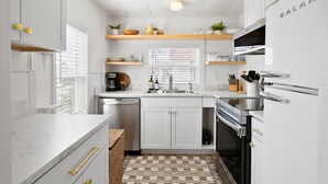A modern kitchen with white cabinetry, a marble countertop, and a patterned floor.