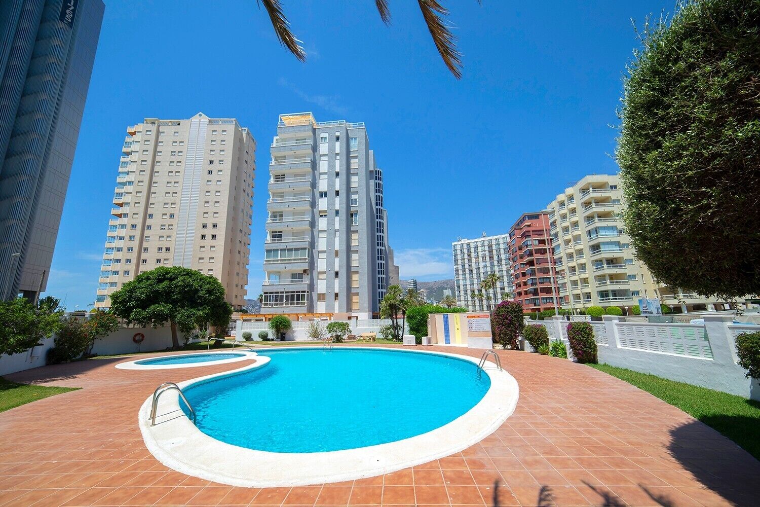 A swimming pool with a tiled deck, surrounded by high-rise residential buildings.