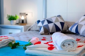 A neatly made bed with rolled towels, a rose, and scattered rose petals. - Apartment 'La Reina' with Sea View, Wi-Fi and Air Conditioning (Calpe)