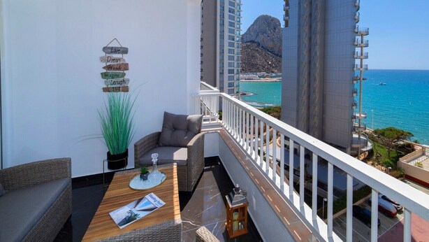 A balcony with wicker furniture, a potted plant, and a sign with motivational words. - Apartment 'La Reina' with Sea View, Wi-Fi and Air Conditioning (Calpe)