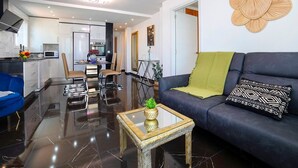 A modern living room with a sofa, a coffee table, and a dining area with chairs and a table. - Apartment 'La Reina' with Sea View, Wi-Fi and Air Conditioning (Calpe)