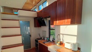 A compact kitchen with wooden cabinets, a built-in oven, and a sink. - The Cyberhut (Underwood)