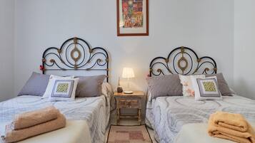 Camera matrimoniale con due letti, ognuno dotato di poggiatesta, comodini, lampade e asciugamani.