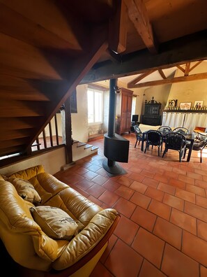 Un accogliente soggiorno con un divano in pelle, un caminetto, un'area pranzo con sedie e una scala.