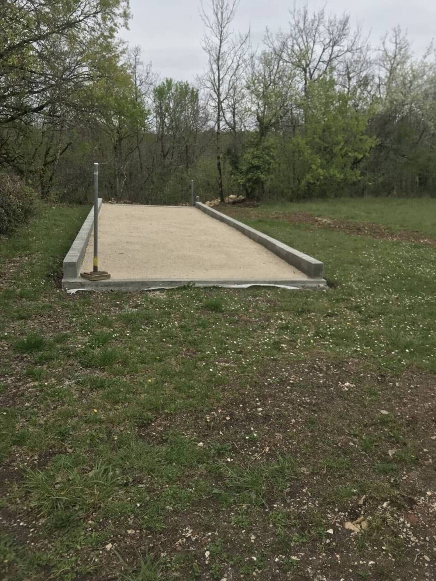 Une structure en béton avec un poteau métallique, située dans une zone herbeuse.