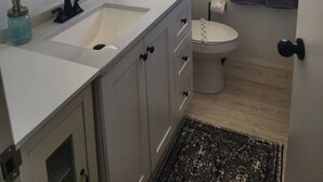 A bathroom with a round mirror, two sinks, a toilet, and a window. - Rural Living Near the Strip in Las Vegas (Las Vegas)