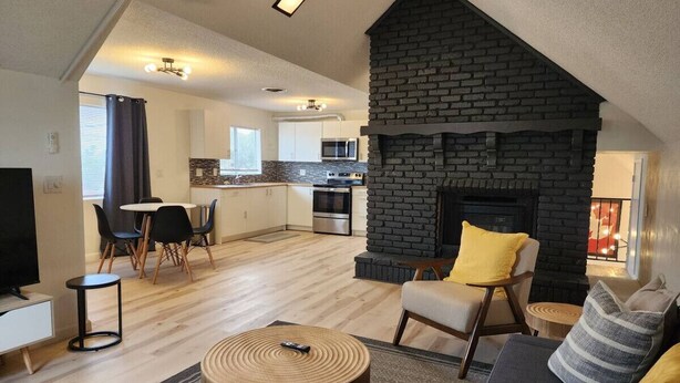 A modern living room with a fireplace, a dining area, and a kitchen in the background. - Rural Living Near the Strip in Las Vegas (Las Vegas)