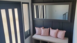 A corner room with a bench, a large mirror, and a door with vertical slats. - Rural Living Near the Strip in Las Vegas (Las Vegas)